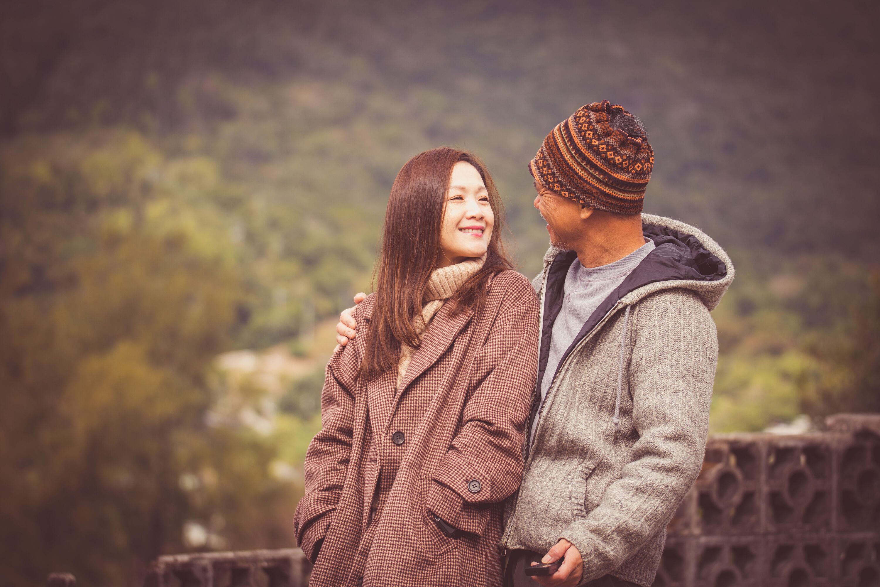 Smiling couple in warm autumn coats standing close together outdoors